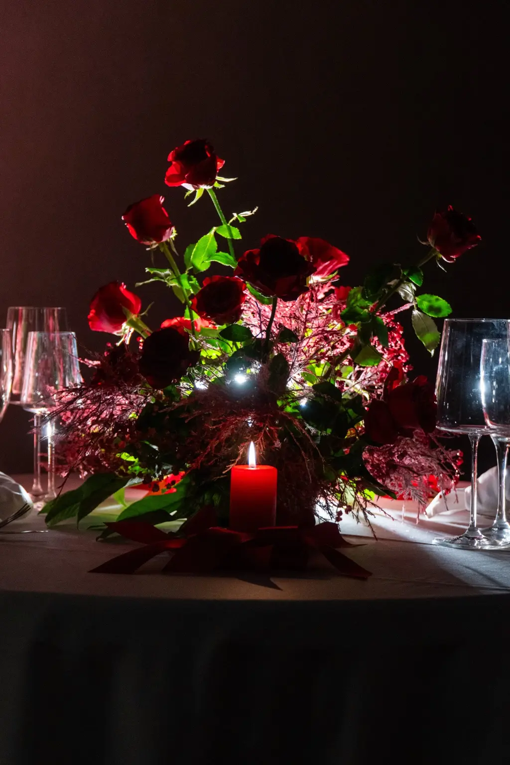 Candlelit wedding table with sculptural red roses and crystal glassware