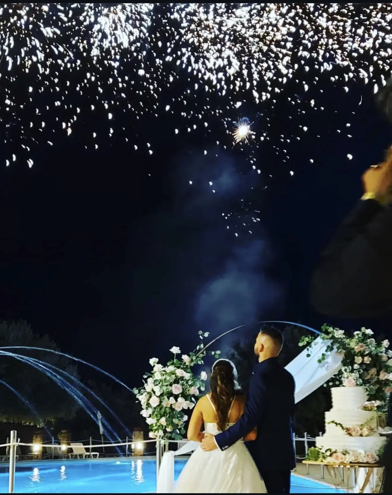 Newlyweds watching fireworks beside their wedding cake during an unforgettable celebration
